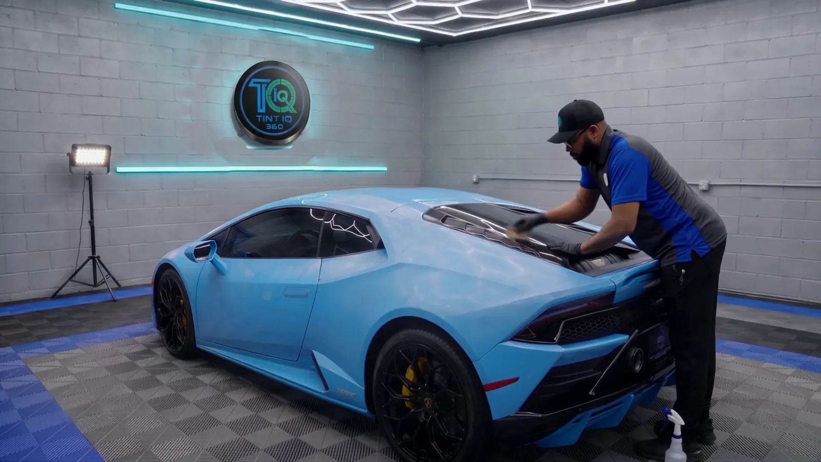 Jay laying window film on the rear glass of a blue Lamborghini Huracán in the shop