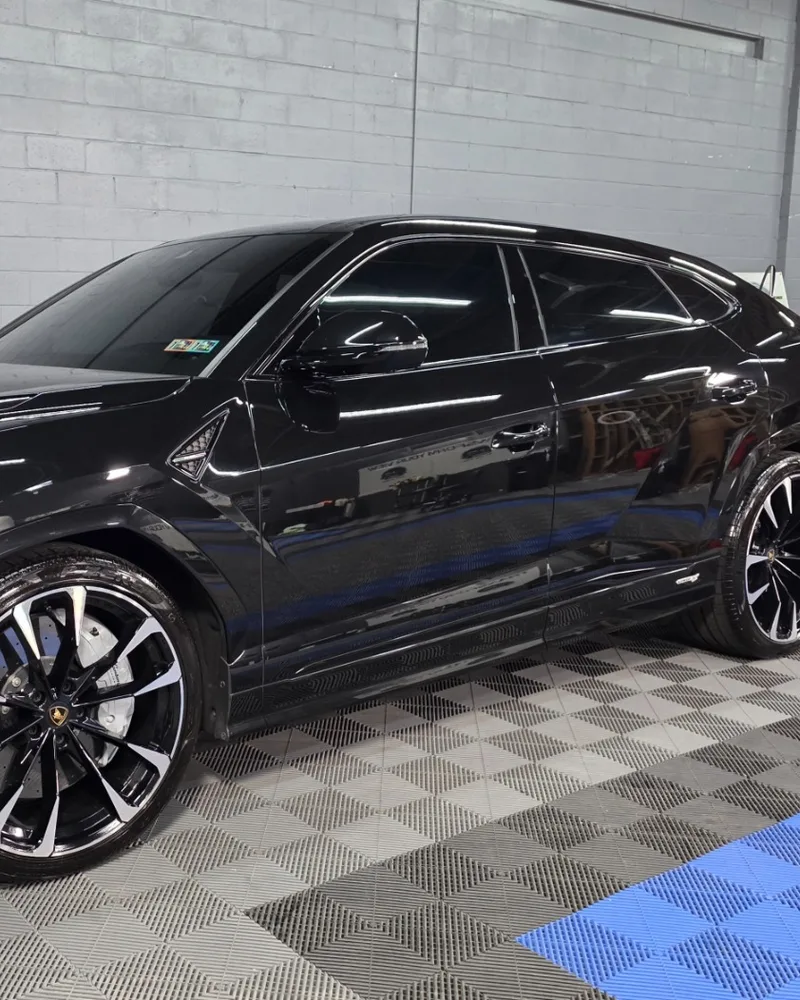 Black Lamborghini Urus with dark tinted side windows in the Tint IQ 360 shop